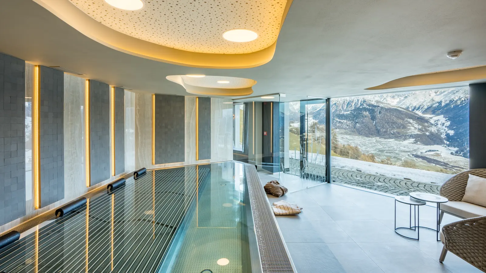 Long pool in the Mountainspa with a panoramic window and a view into the valley