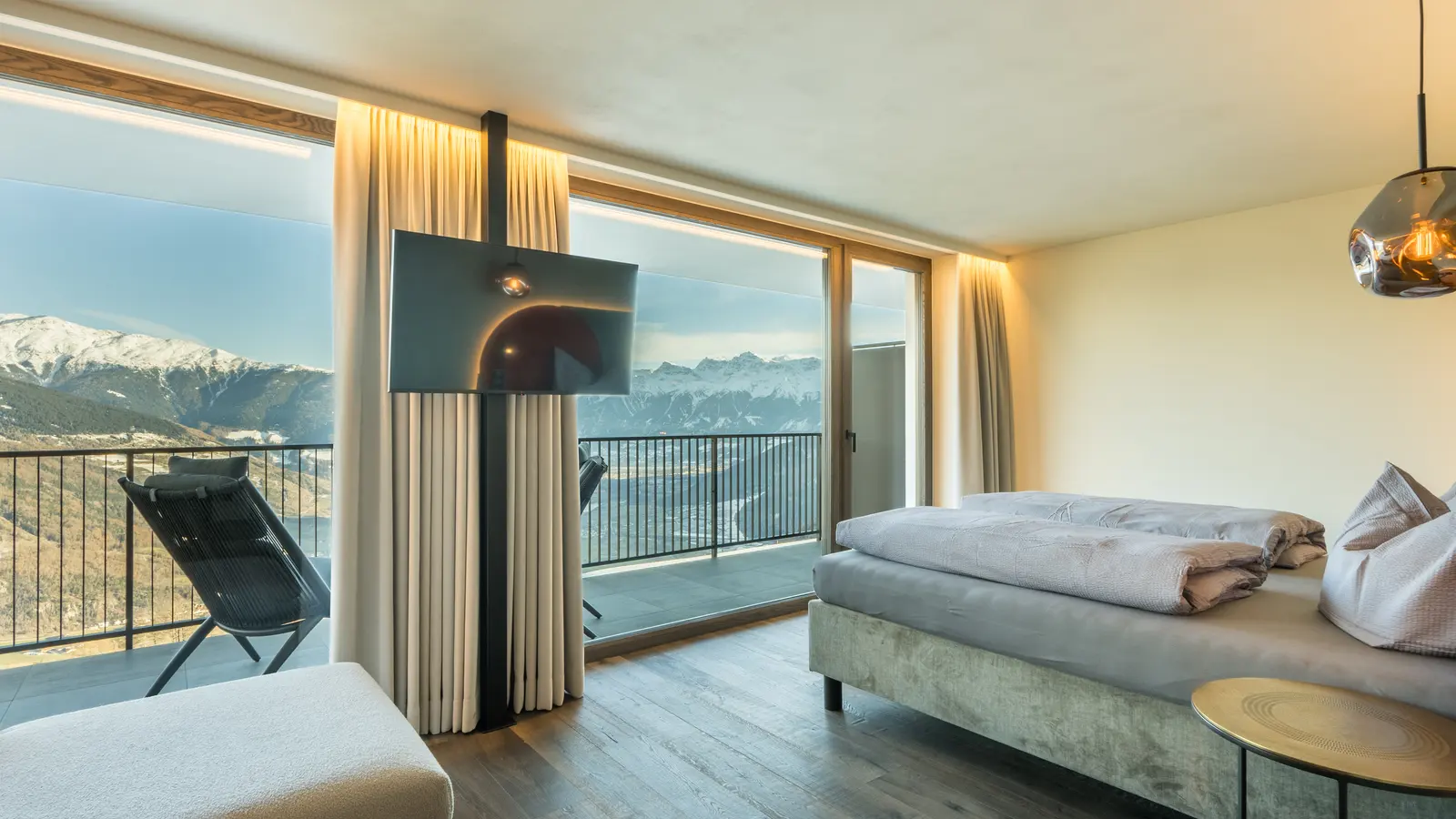 Room with a double bed, large windows and a balcony with mountain views